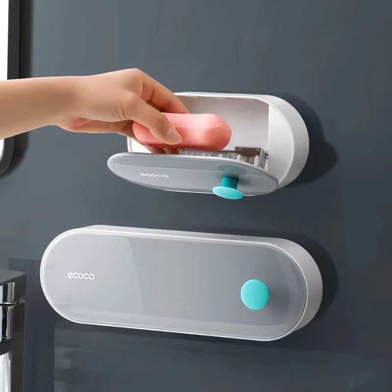 Minimalist gray wall-mounted Ecoco soap box with a flip-open design and blue button, ideal for tidy bathroom storage.