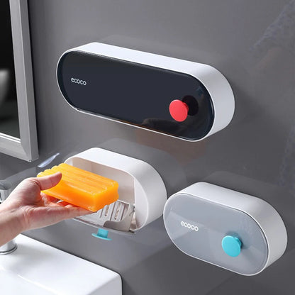 Compact wall-mounted Ecoco soap storage with a sleek gray design and blue button, keeping soap dry and mess-free.

