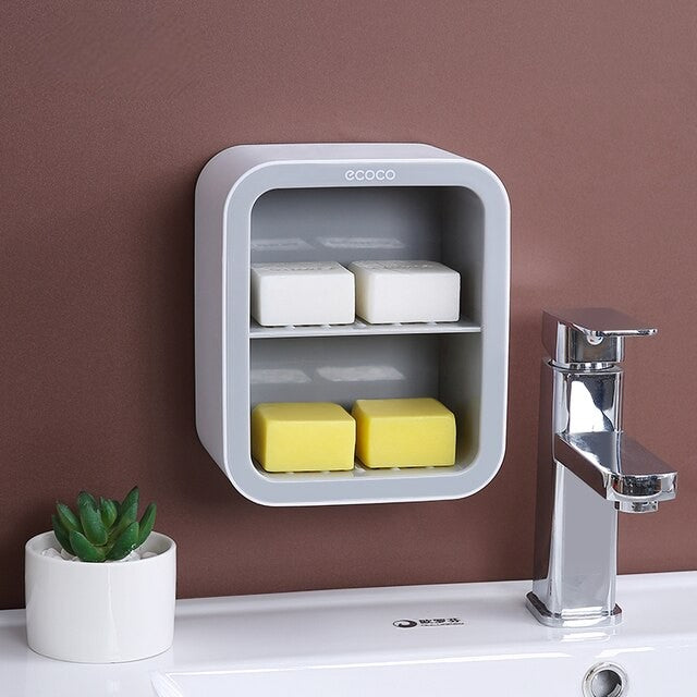 Sleek wall-mounted soap holder with double compartments for convenient storage of soaps and sponges in bathrooms or kitchens.

