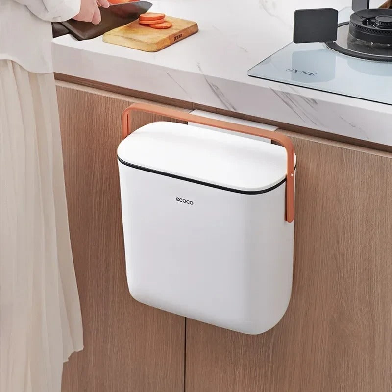 White Ecoco trash bin with orange handle, designed for easy cabinet mounting and convenient waste disposal in the kitchen.

