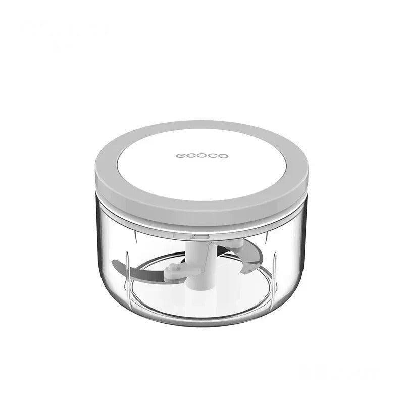 Small manual food chopper with a clear container and a white lid, designed for finely mincing garlic, spices, and herbs.

