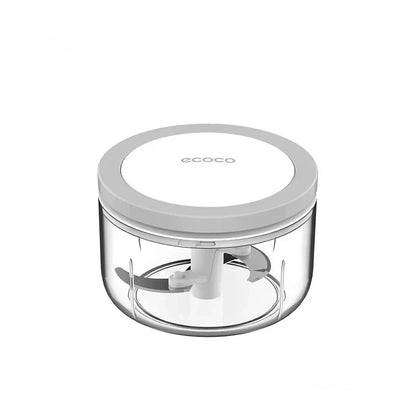 Small manual food chopper with a clear container and a white lid, designed for finely mincing garlic, spices, and herbs.

