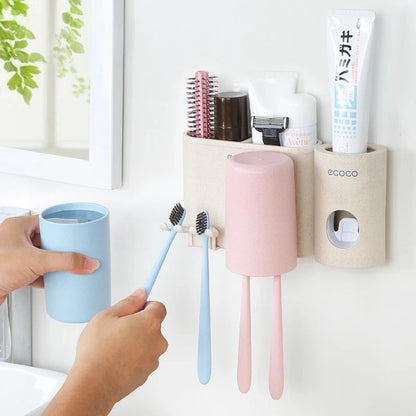 Wall-mounted toothbrush holder with pastel cups, storage compartments, and toothpaste dispenser for organized bathroom essentials.

